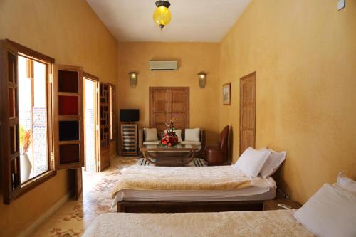 a bedroom with two beds and a table in it at Riad Ben in Marrakesh