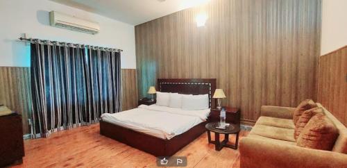 um quarto com uma cama, um sofá e uma cadeira em Mulberry Guest House F-10 em Islamabad