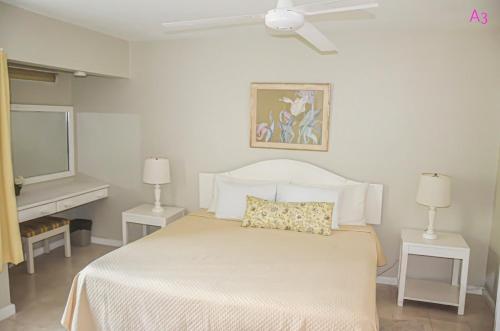 a white bedroom with a bed and a television at Condo Rios Resort in Ocho Rios