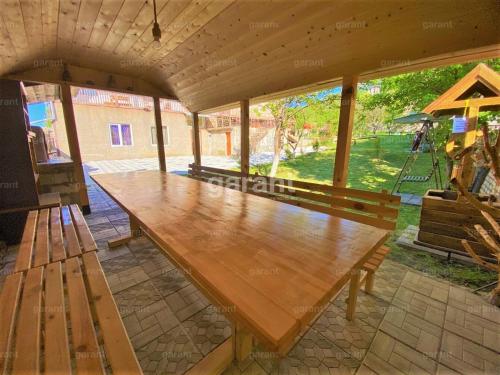 - une grande table en bois dans un pavillon avec une balançoire dans l'établissement BIG HOUSE, à Dilidjan