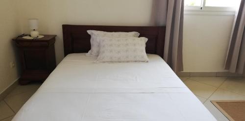 a bed with white sheets and pillows in a room at Suite Villa au bord de la mer chez Saloua in Chirongui