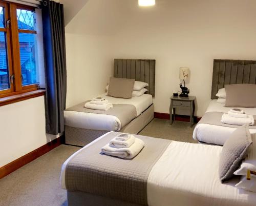 フォート・ウィリアムにあるVictoria House Bed and Breakfastのベッド3台と窓が備わる客室です。