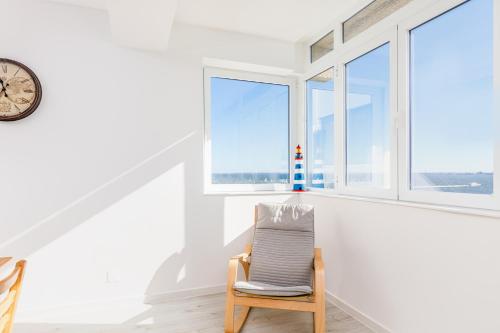 uma cadeira num quarto branco com janelas em DORA'S HOME em Cacilhas