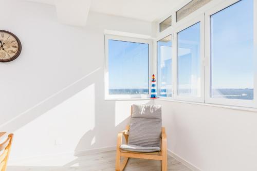 a chair in a white room with windows at DORA'S HOME in Almada
