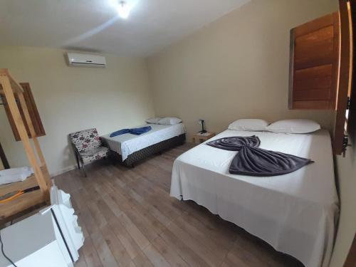 a hotel room with two beds and a chair at Vila Itacimirim in Itacimirim