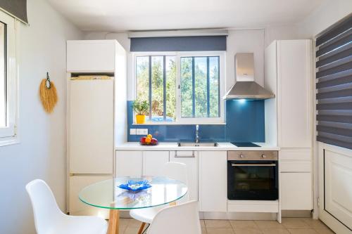 cocina con mesa de cristal y armarios blancos en Coco Studio en La Canea