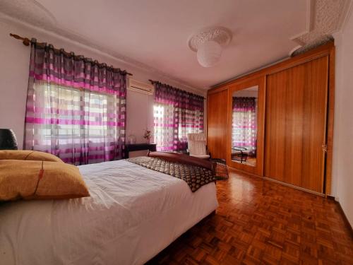 a bedroom with a large bed and pink curtains at Modern & Cosy Apartment in Fundão Centre in Fundão