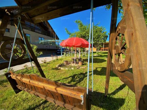 a swing with a red umbrella in a park at BIG HOUSE in Dilijan