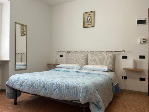 a bedroom with a bed with a blue comforter and a mirror at camere Rosignoli in Assisi