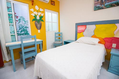 um quarto com uma cama e duas cadeiras azuis em La Casa Del Almendro em Playa del Carmen