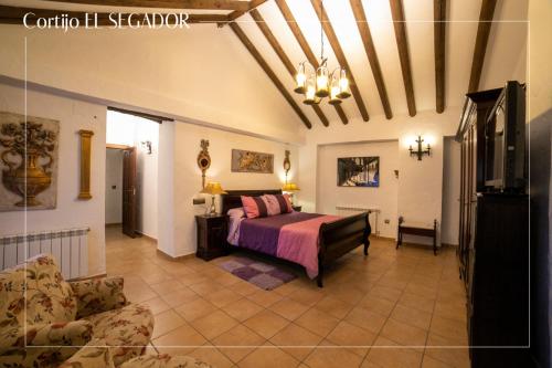 een slaapkamer met een bed en een bank in een kamer bij Cortijo El Segador y El Capricho in Almedinilla