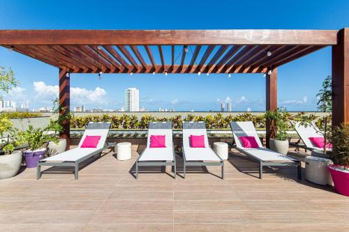 a group of chairs on a patio with a view at TOLIVE One Housi Recife by Carpediem in Recife