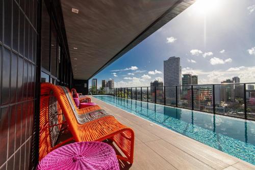 un balcón con bancos y una piscina en un edificio en TOLIVE One Housi Recife by Carpediem, en Recife