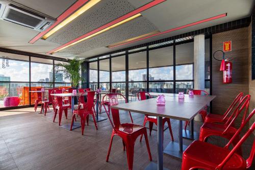a restaurant with red chairs and tables and windows at TOLIVE One Housi Recife by Carpediem in Recife