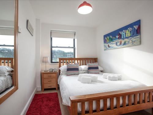 um quarto com uma cama com lençóis brancos e almofadas em Cove View em Porthcurno