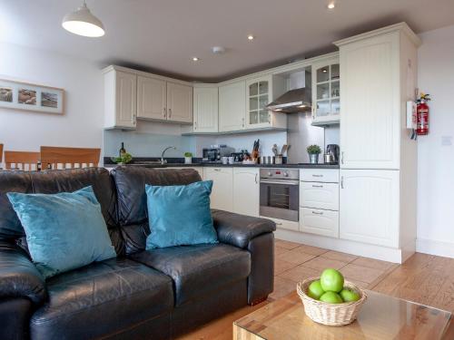 uma sala de estar com um sofá e uma cozinha em Cove View em Porthcurno