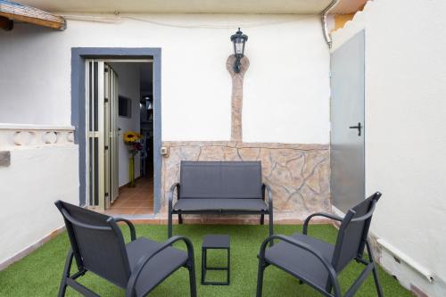 a patio with two chairs and a bench on the grass at EDEN RENTALS Atogo Cozy Apartment in Granadilla de Abona