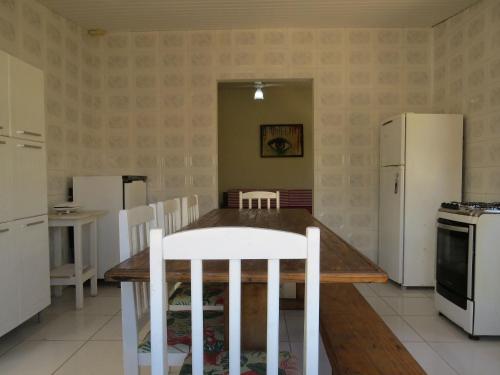 eine Küche mit einem Holztisch und weißen Geräten in der Unterkunft Casa com Piscina e Churrasqueira perto da Praia in Pontal do Paraná