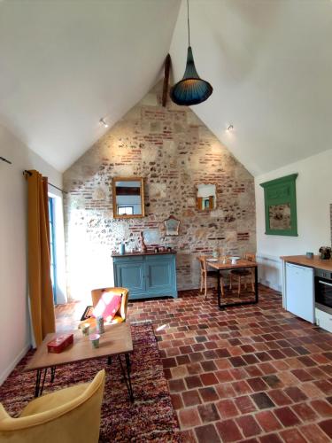 - un salon avec un mur en briques et une table dans l'établissement Le gite du pré dorė, à Bonneville-la-Louvet