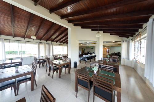 un restaurante con techos de madera, mesas y sillas en Class Hotel Passos Rio Grande Portal da Canastra en Passos