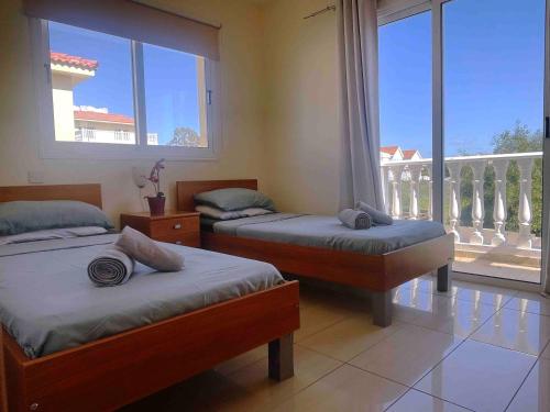 阿依纳帕Nissi Beach Golden Villas的一间有两张床和一扇大窗户的卧室