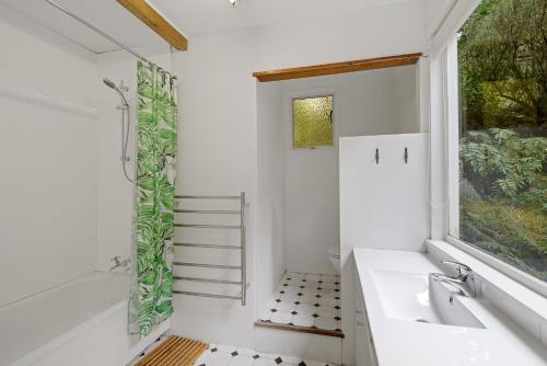 een witte badkamer met een wastafel en een raam bij Holiday Chalet in Arthurs Pass in Arthur's Pass