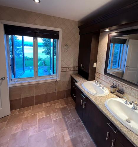 a bathroom with two sinks and a window at Villa Delrose Waterfront - No party in Montreal