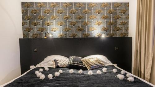 a bed with a black headboard and pillows on it at Gîtes des lacs - Pinatelle - Durtol in Durtol