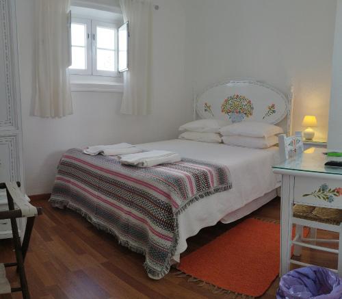 ein Schlafzimmer mit einem Bett mit einer Decke und einem Fenster in der Unterkunft Mont' Sobro House Rooms in Évora