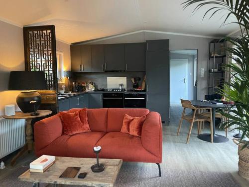 een woonkamer met een rode bank en een keuken bij Luxe vakantiehuis “Saalien” in Beekbergen