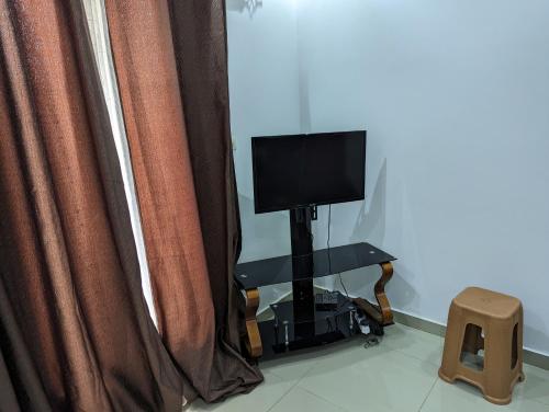 a television sitting on a stand in front of curtains at MBAO Sipres Appartement moderne bord de mer in Mbaw