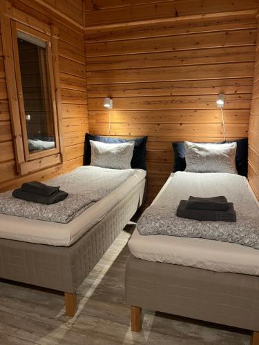 two beds in a room with wooden walls at Cottage by the sea in Hanko