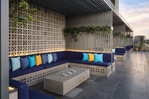 a patio with a blue couch with colorful pillows at voco Guadalajara Neruda by IHG in Guadalajara