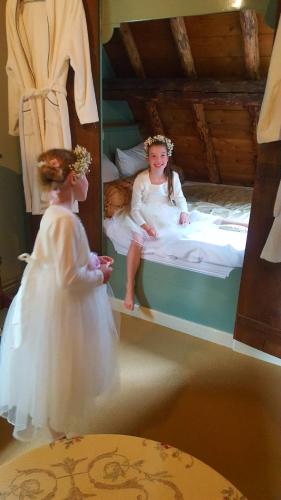 a little girl in a wedding dress sitting on a bed at B&B Het Gasthuys in Amerongen