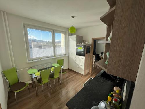 a kitchen with a table and green chairs in a room at Svit apartment High Tatras in Svit