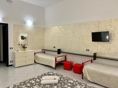 a bedroom with two beds and a tv on the wall at Ohana by Casimiro in Trapani