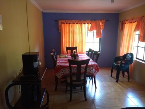 a dining room with a table and chairs and windows at Posada Nativa Miss Casira in San Andrés