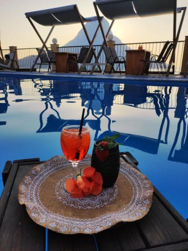 a drink on a plate next to a swimming pool at Fatolitis Studios in Masouri