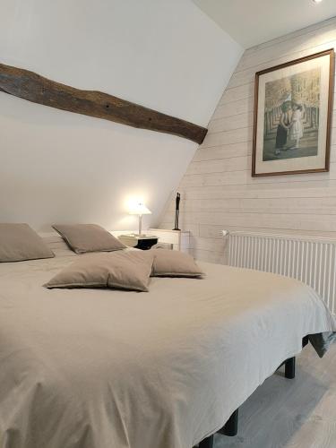 une chambre avec un grand lit blanc avec un tableau sur le mur dans l'établissement La Maraiquaise, à Marais-Vernier