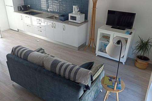 a living room with a blue couch and a kitchen at Perto do Mar, Alojamento Local - Espaço T2 privativo in Vagos