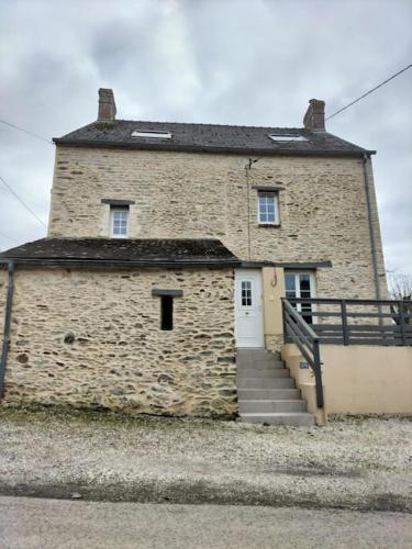 a large brick building with a staircase in front of it at Les 3 Pommiers : gîte en Suisse Normande in Donnay