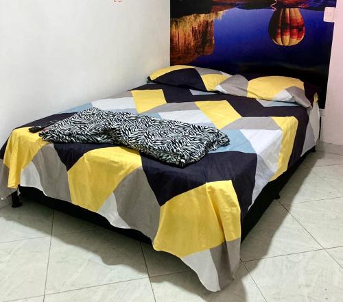 Una cama con una manta negra y amarilla. en BARU ESTELAR, en Medellín