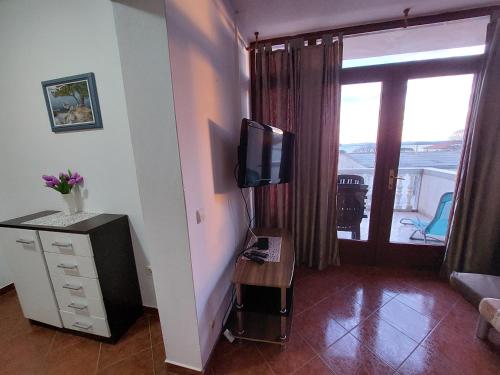 ein Wohnzimmer mit einem TV und ein Zimmer mit einem Balkon in der Unterkunft Apartman Vukoja Pakostane in Pakoštane