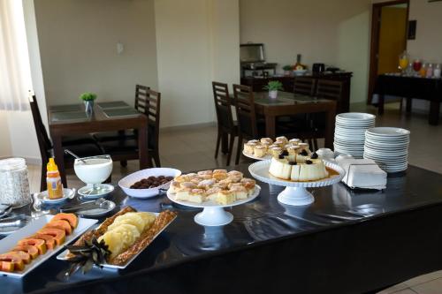 a table topped with different types of cakes and pastries at Class Hotel Passos Rio Grande Portal da Canastra in Passos