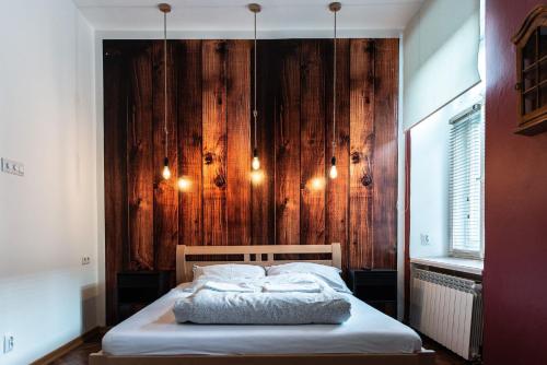 a bed in a room with a wooden wall at Apartament Cafe Belg in Częstochowa