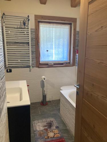 bagno con lavandino, vasca e finestra di Chalet Gorret a Torgnon