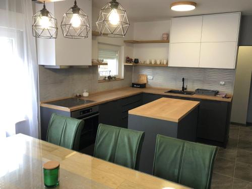 uma cozinha com armários brancos e uma mesa com cadeiras verdes em Vila ISKRA em Novi Sad