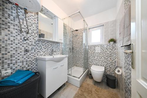 uma casa de banho com um WC, um lavatório e um chuveiro em Apartmani Miluška em Sveti Filip i Jakov