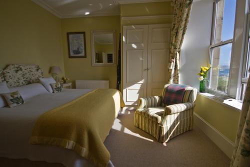 a bedroom with a bed and a chair and a window at Loch Gorm House in Bruichladdich