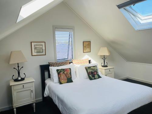 Un dormitorio con una cama blanca con almohadas. en The Cottage at 95a - self contained, quiet and peaceful en Big Omaha
